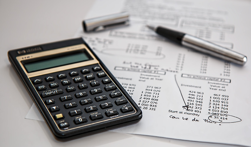 calculator and pen next to financial reports