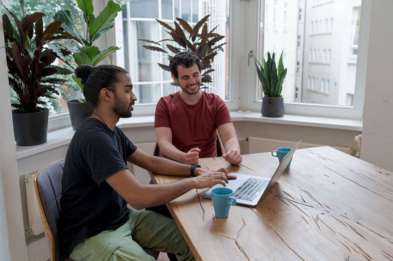 Image of two people looking at a laptop screen on a table.